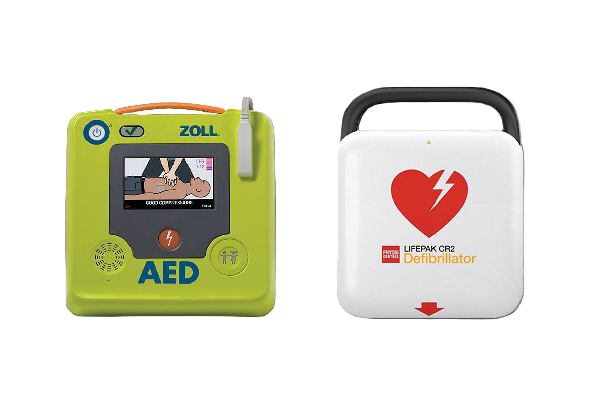 Two automated external defibrillators (AEDs), one with a green casing labeled ZOLL and the other with a white casing labeled LIFEPAK CR2.